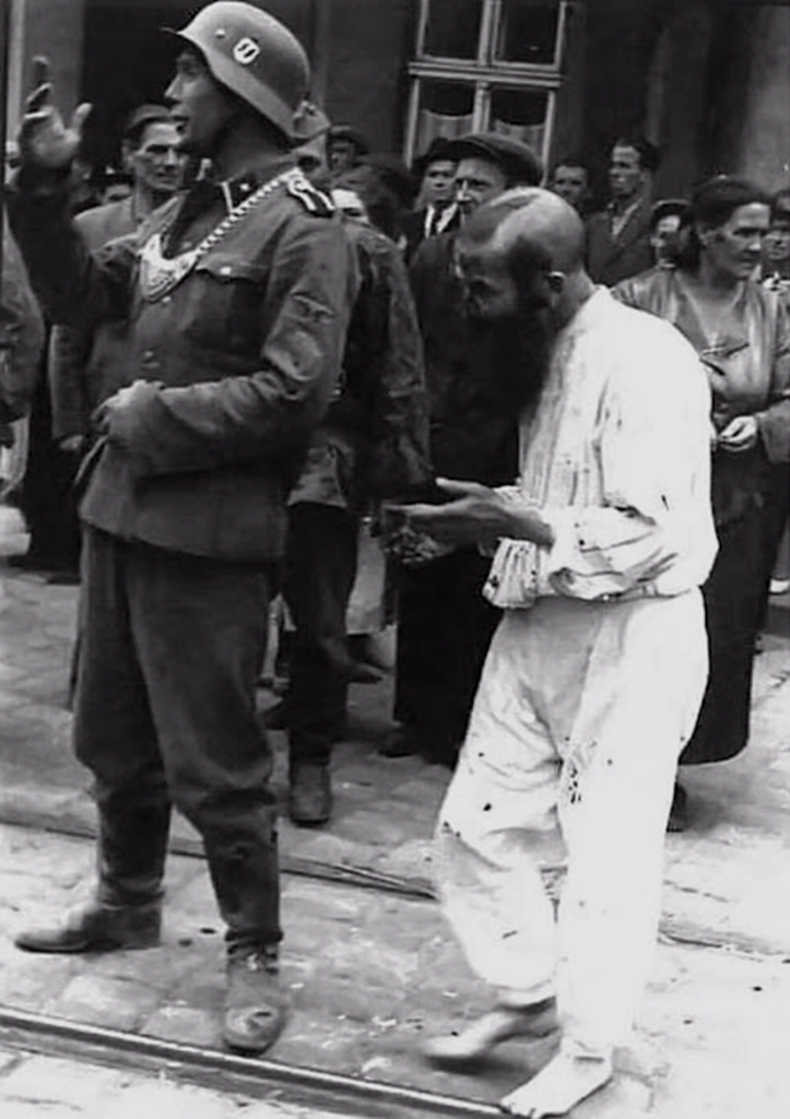 Солдат СС издевается над раввином, которому насильно постригли бороду и волосы на голове