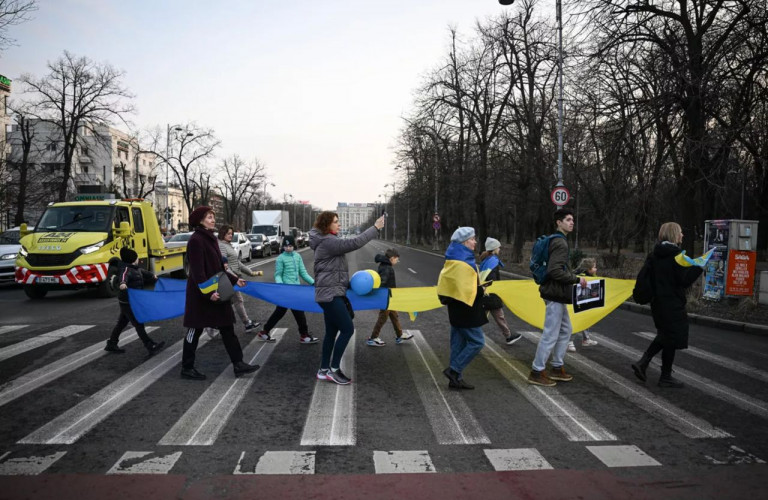 На фото: Українські біженці на вулицях Бухареста. Однак ходіння с прапорами вже не вражає, а намагання завадити дорожньому руху не викликає співчуття, а дратує