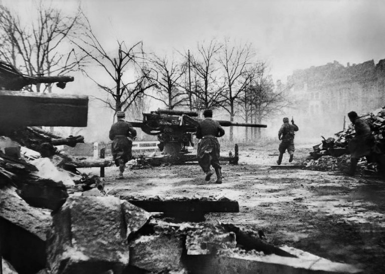 Заглавное фото. Советские бойцы пробегают возле немецкого 88-мм зенитного орудия Flak 37 во время боёв в Бреслау. Февраль-март 1945-го