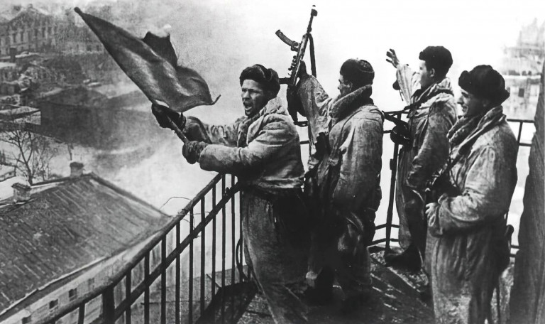 Заглавное фото. Советские солдаты поднимают красный флаг над освобожденной Гатчиной 26 января 1944 года